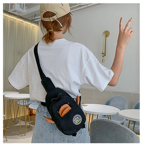 Detail of cute monster canvas sling bag with orange dorsal fins on a black fabric background