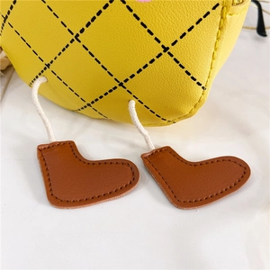 Détail d'un sac en cuir matelassé jaune avec pendentifs chaussures et coutures fines