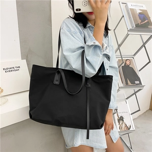 Detail of a large black waterproof nylon tote bag with shoulder straps for women