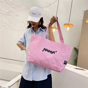 Detail of the pink canvas tote bag showing the NNNVN print and the Cressida brand label