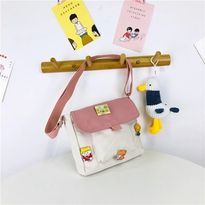 Détail d'un sac bandoulière en toile avec touches roses et badges de dessin animé