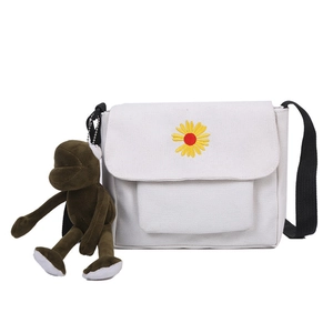 White canvas crossbody bag with daisy embroidery and a small brown monkey charm