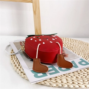 Detail of red strawberry children crossbody bag with cute feet and cartoon face