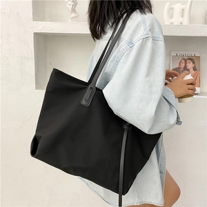 Detail of the large black tote bag featuring premium nylon material and slim leather straps