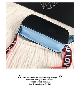 Détail du sac bandoulière bleu et noir avec une large sangle à lettres tendance
