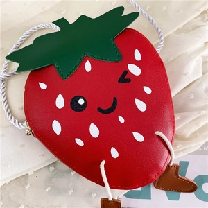 Close-up of strawberry-shaped girl crossbody bag with cute face and leaf detail