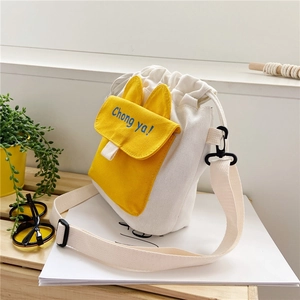 Detail of white canvas drawstring bucket bag with yellow rabbit ear pocket and strap