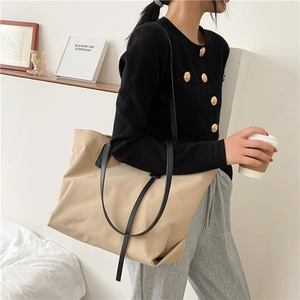 Minimalist beige tote bag detail showing large capacity design with slim black shoulder straps