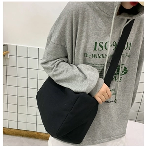 Dettaglio di una grande borsa a tracolla in tela nera che mostra capienza e vestibilità