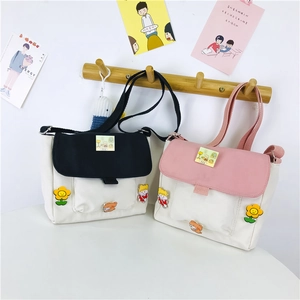 Détail de sacs bandoulière en toile avec écussons de dessins animés et sangle réglable