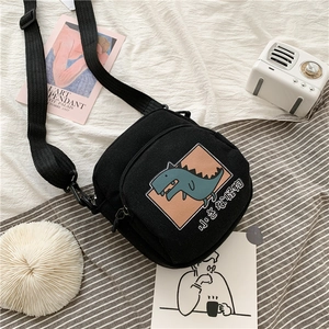 Détail du sac bandoulière en toile noire avec dinosaure mignon et sangle réglable