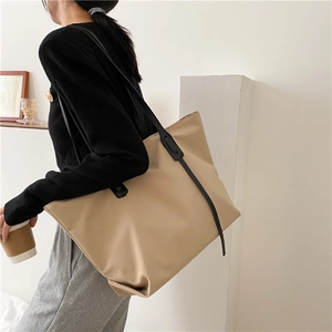 Side view of beige large-capacity tote bag worn by model in a minimalist lifestyle setting