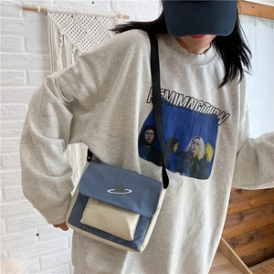 Detailed shot of blue and beige canvas crossbody bag featuring planet embroidery and strap