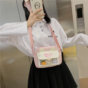 Detail of pink canvas crossbody bag featuring a transparent PVC window and cute 3D charms