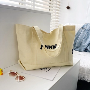 Detailed close-up of large canvas tote bag showing black graphic prints on cream fabric