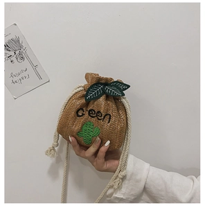 Detail of woven straw bucket bag featuring green cactus embroidery and drawstring closure