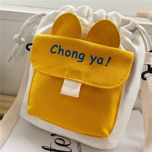 Detail of canvas drawstring bucket bag with yellow animal ear pocket and Chong ya text