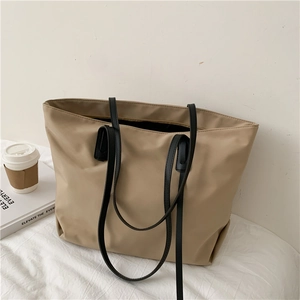 Minimalist beige tote bag with black straps and accessories for a lifestyle look