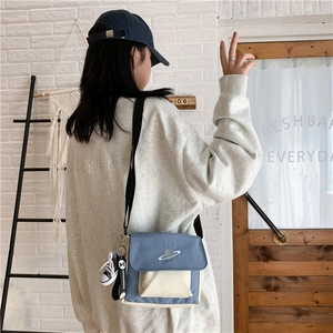 Detail of blue and beige canvas crossbody bag with planet embroidery and side sneaker charm