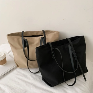 Detail view of khaki and black minimalist tote bags in nylon with slim PU leather shoulder straps