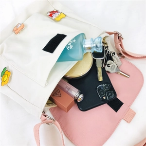 Détail montrant l'intérieur spacieux du sac à bandoulière en toile beige et rose