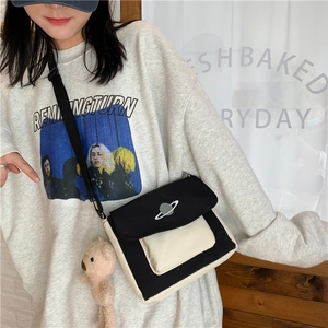 Close-up of canvas crossbody bag featuring star embroidery and a plush bear pendant