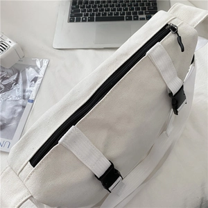 Detail of white canvas crossbody bag showing black zipper and adjustable strap buckle