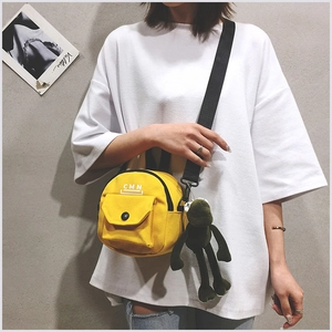 Détail du sac bandoulière rond en toile jaune avec sangle et pendentif grenouille