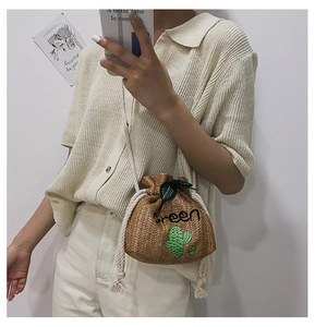 Detail of straw bucket bag featuring green cactus embroidery and white rope strap