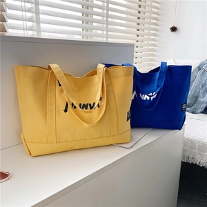 Detail of vibrant yellow and royal blue canvas tote bags with ANNVI logo branding