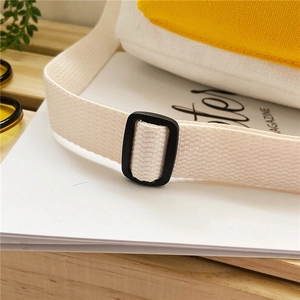 Close-up of canvas bag with yellow stitching and black plastic strap adjuster buckle