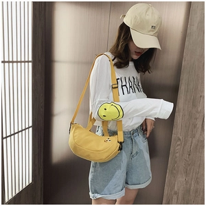 Détail du sac bandoulière en toile jaune avec visage brodé mignon et bandoulière réglable