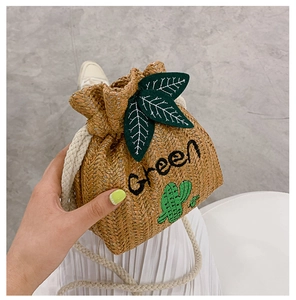 Detail of straw bucket bag featuring Green embroidery, cactus patch and leaf drawstring