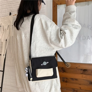 Detail of canvas crossbody bag with planet embroidery and daisy brand charm detail