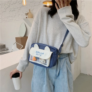 Detail of blue canvas crossbody bag with rabbit ears and clear display pocket