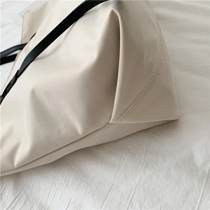 Close-up of soft beige PU leather tote with black strap showing fine stitching detail