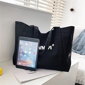Detailed view of large black canvas tote bag with white lettering showing interior capacity