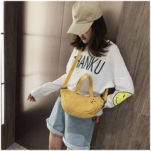 Détail du sac demi-lune en toile jaune avec motif smiley brodé et large bandoulière