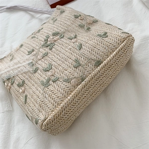 Lace-trimmed straw tote bag featuring floral embroidery and woven fabric straps
