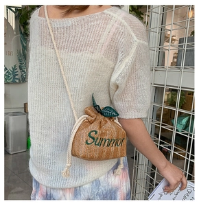 Detail of straw bucket bag with Summer embroidery and green leaf drawstring top
