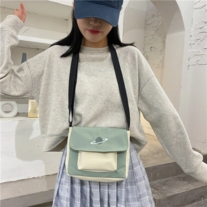 Detail of mint green and cream canvas crossbody bag with planet embroidery and black strap