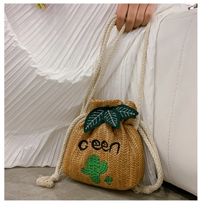 Detail of hand-woven straw bucket bag featuring green cactus embroidery and cotton rope strap