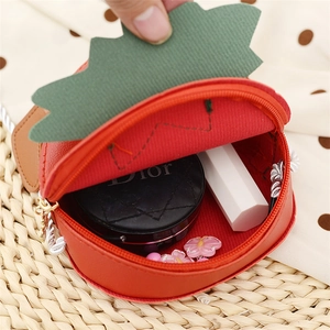 Detail showing the inner space of a strawberry-shaped kids purse with small cosmetics