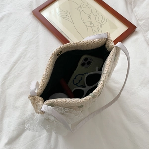 Straw woven bucket bag with lace bow decoration showing large capacity and interior items