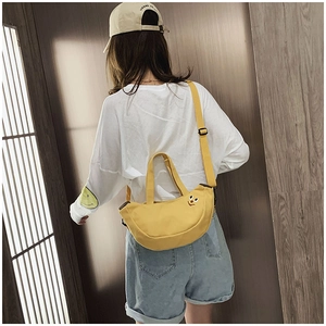 Détail du sac croissant en toile jaune brodé porté par un mannequin féminin