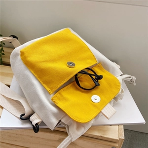 Detail of canvas bag with two yellow front pockets and magnetic buckle closure