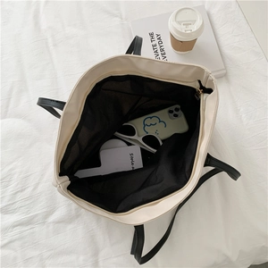 Close-up of cream tote bag interior showing large capacity and black contrast lining