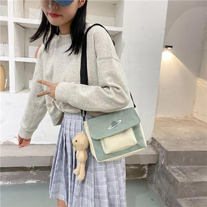 Detail of canvas crossbody bag in mint green with planet embroidery and teddy bear charm