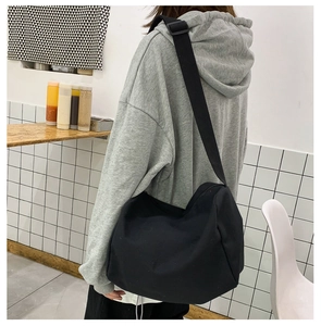 Vista posteriore di una modella con borsa a tracolla in tela nera e ampia cinghia