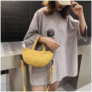 Détail d'un sac banane jaune en toile avec visage brodé et bandoulière réglable